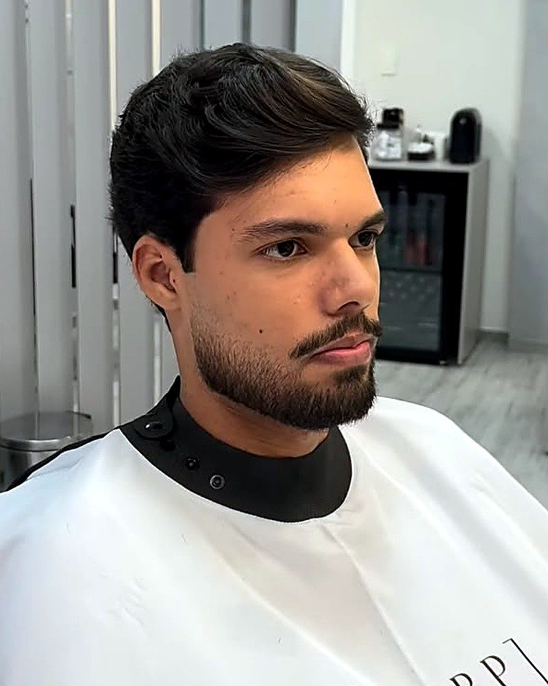 Corte social com volume para trás e barba desenhada, visto de perfil