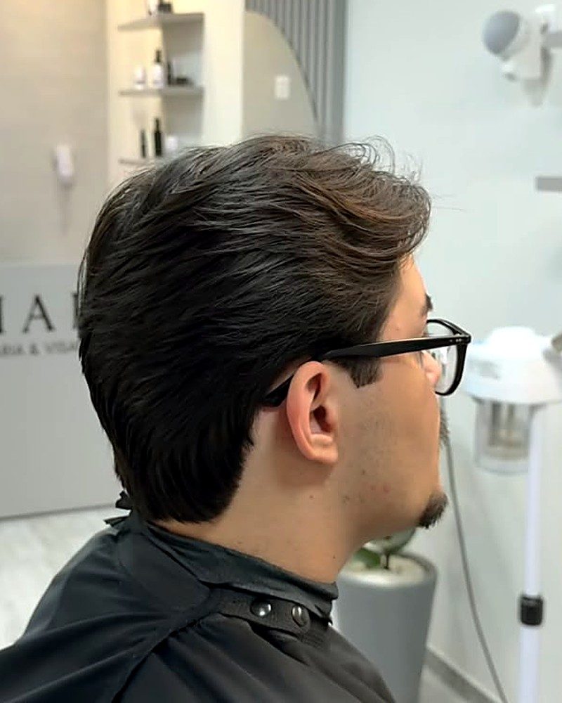 Corte médio com volume penteado para trás, visto de perfil